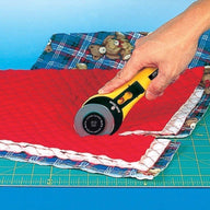 Photo of 60mm rotary cutter cutting though multiple lays of fabric on an OLFA cutting board