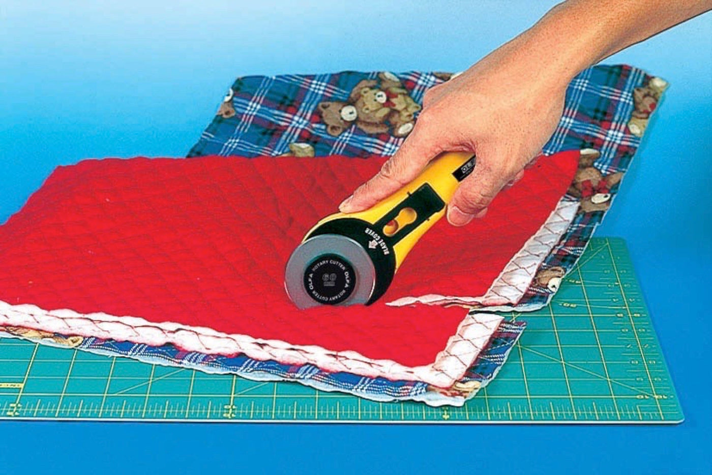 Photo of 60mm rotary cutter cutting though multiple lays of fabric on an OLFA cutting board