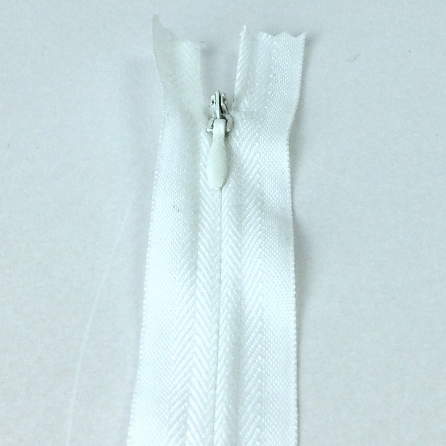 Photo of white invisible or concealed zips available in many different colours and sizes. Great for achieving a professional finish in your products. Invisible zippers are perfect for dressmaking, cushions, crafts, etc., where you don't want your zipper showing. Installing them can be tricky without the right foot on your machine; a normal zipper foot is for installing standard zippers, while you will need an invisible zipper foot for a professional result