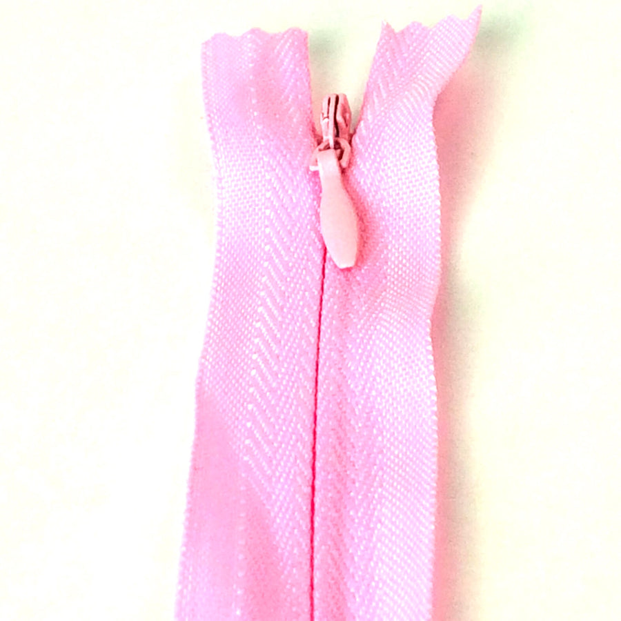 Photo of light pink invisible or concealed zips available in many different colours and sizes. Great for achieving a professional finish in your products. Invisible zippers are perfect for dressmaking, cushions, crafts, etc., where you don't want your zipper showing. Installing them can be tricky without the right foot on your machine; a normal zipper foot is for installing standard zippers, while you will need an invisible zipper foot for a professional result