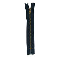 A single black zipper with a gold-toned metal pull tab, placed vertically on a textured off-white paper background.
