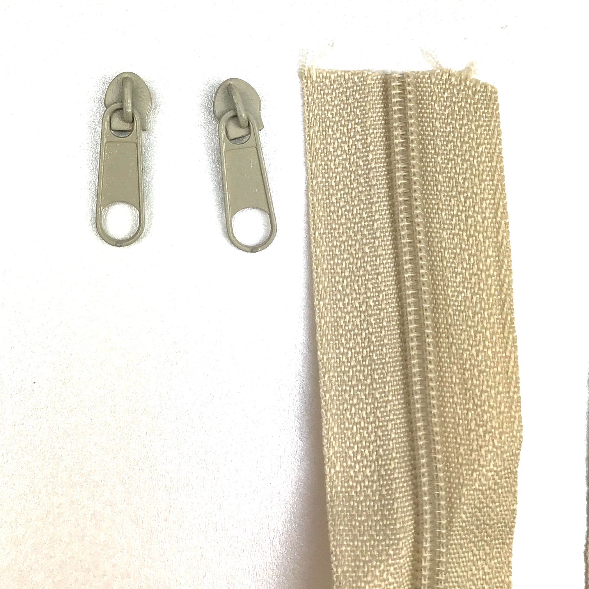 Beige Continuous standard zipper tape and sliders with pullers: Versatile zipper components designed for various applications. The continuous tape allows for customizable lengths, while the sliders and pullers ensure smooth operation and secure closure. Ideal for a wide range of projects, from apparel to accessories, offering functionality and durability. Upgrade your designs with dependable standard zipper tape and sliders complete with convenient pullers