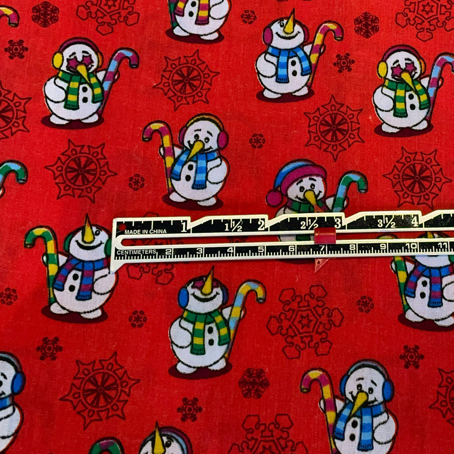 Red fabric with snowman pattern and a ruler for scale