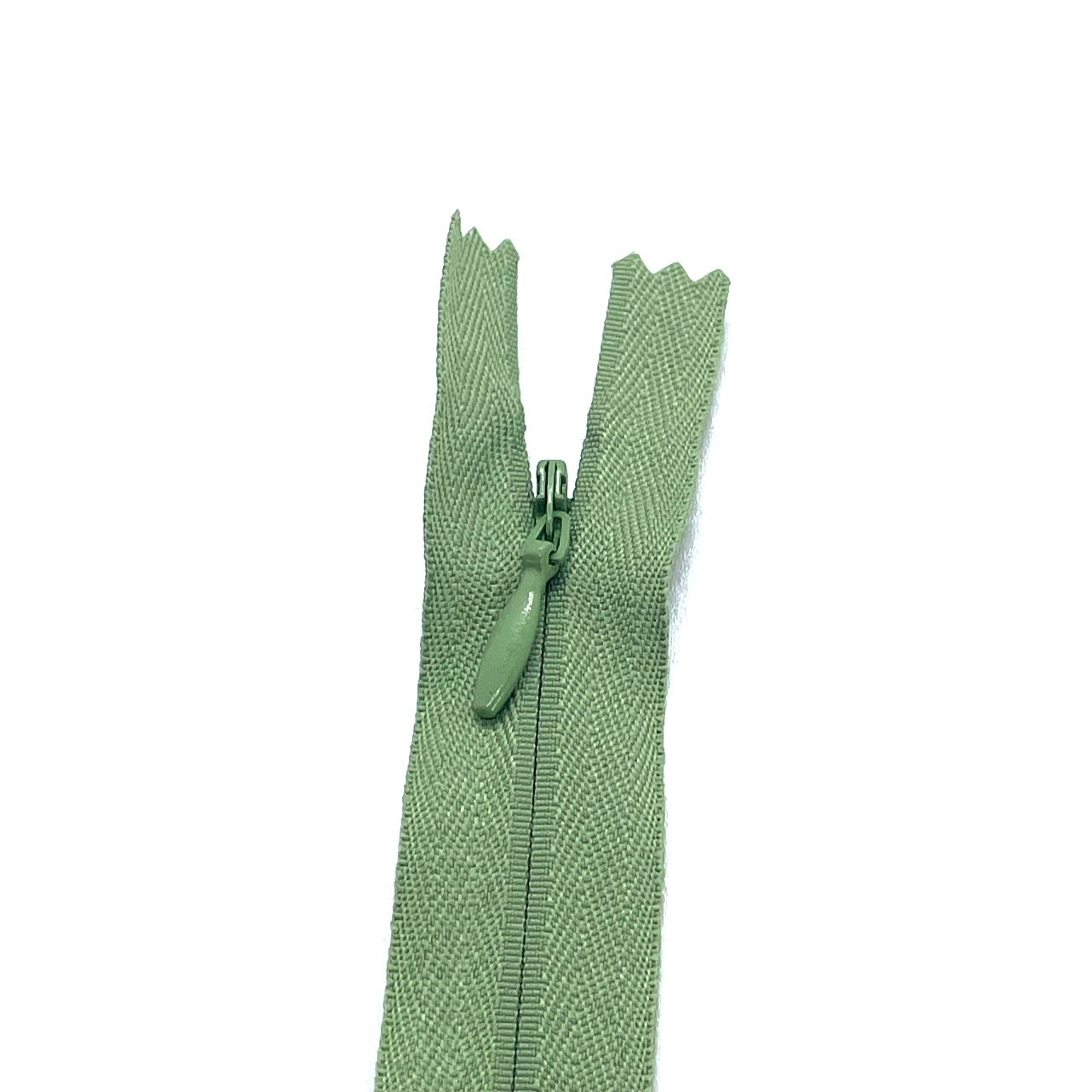 Photo of dusky sage green invisible or concealed zips available in many different colours and sizes. Great for achieving a professional finish in your products. Invisible zippers are perfect for dressmaking, cushions, crafts, etc., where you don't want your zipper showing. Installing them can be tricky without the right foot on your machine; a normal zipper foot is for installing standard zippers, while you will need an invisible zipper foot for a professional result