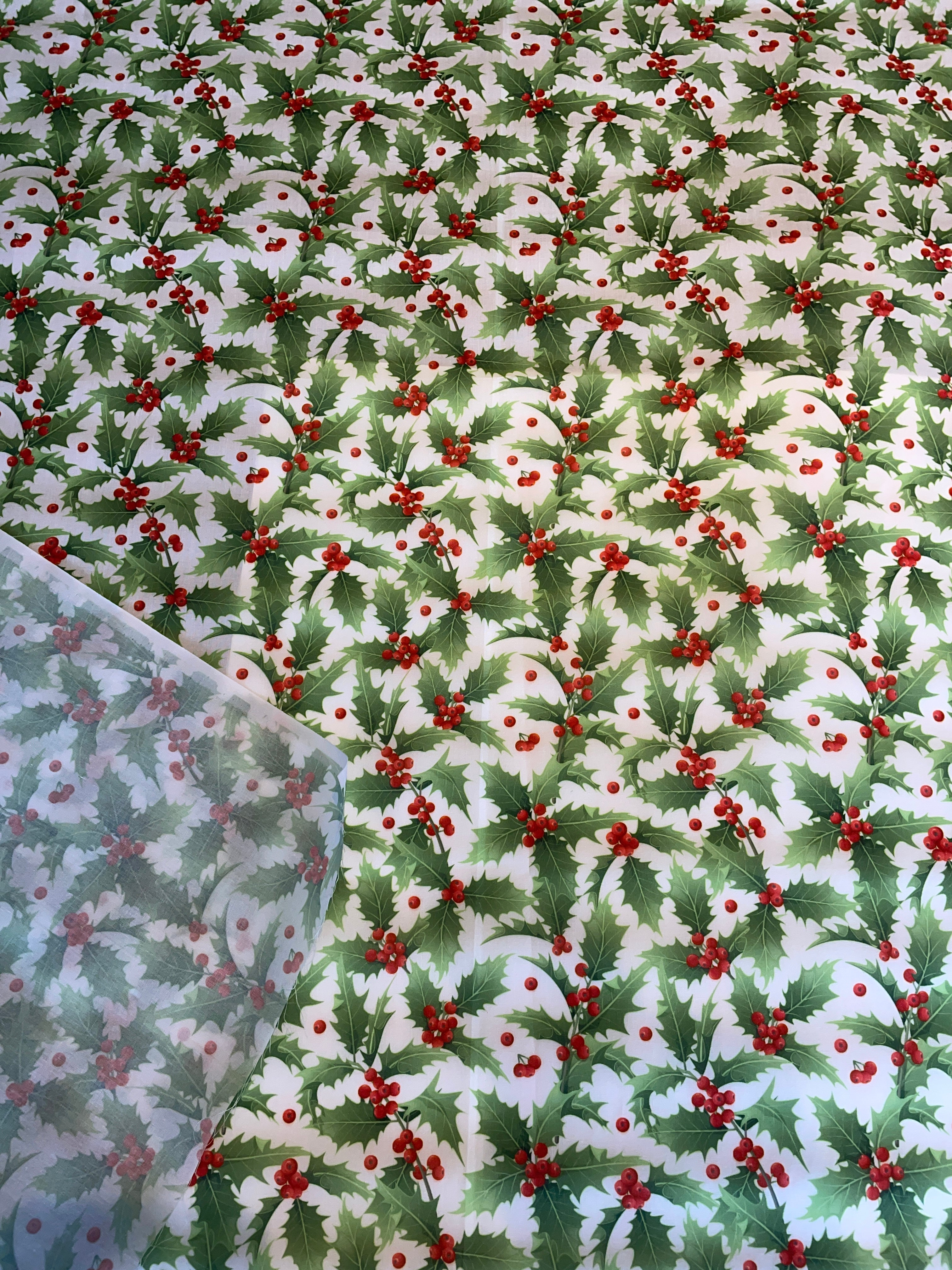 Patterned fabric with green leaves and red berries on a white background