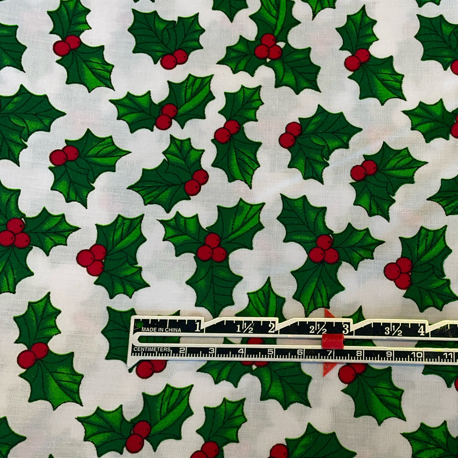 Pattern of green holly leaves and red berries on a white background with a ruler at the bottom.