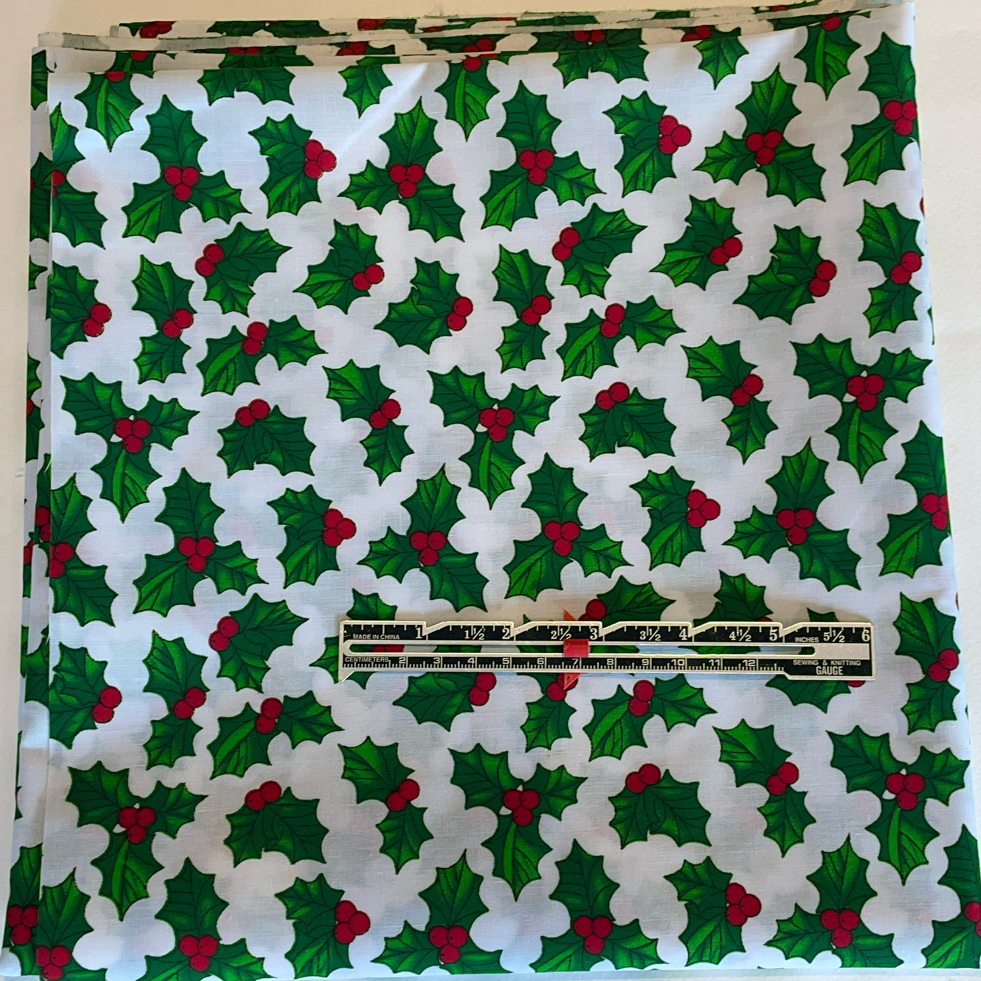 Christmas-themed fabric with holly pattern and a ruler for scale.