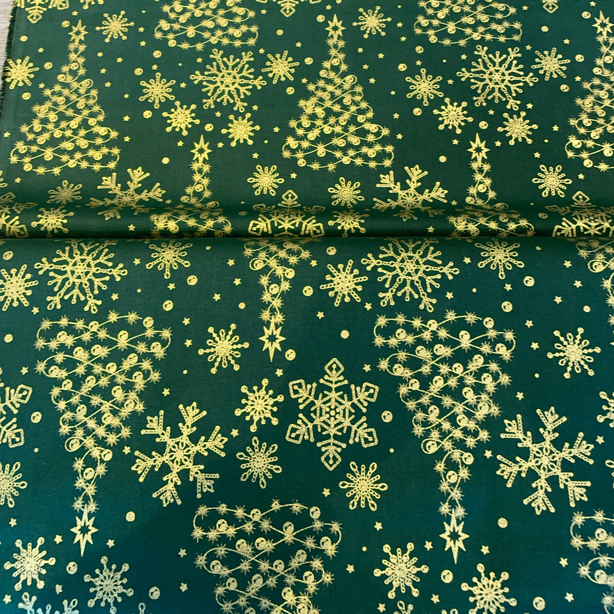 green cotton fabric with printed golden christmas trees and snowflakes