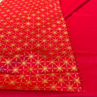 Red fabric with a repeating gold geometric star pattern, folded to show texture and weave, set against a matching solid red background.