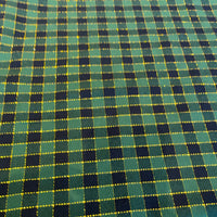 A close-up of a green and black plaid fabric with thin yellow dotted lines forming the grid pattern.