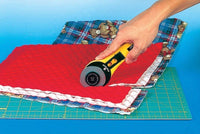 Photo of 60mm rotary cutter cutting though multiple lays of fabric on an OLFA cutting board