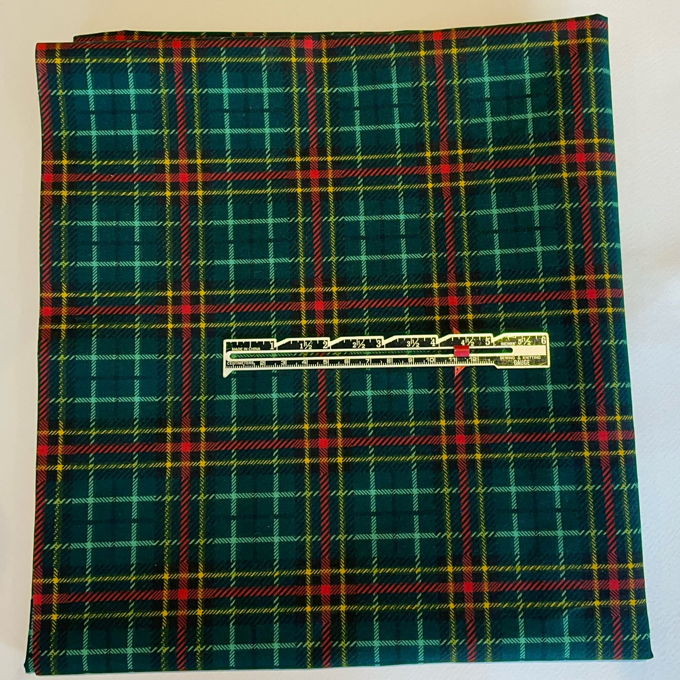 Green plaid fabric with a visible brand label on a white background