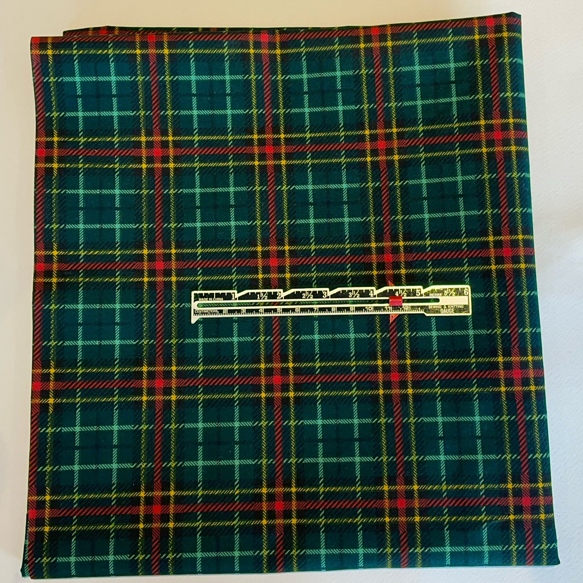 Green plaid fabric with a visible brand label on a white background