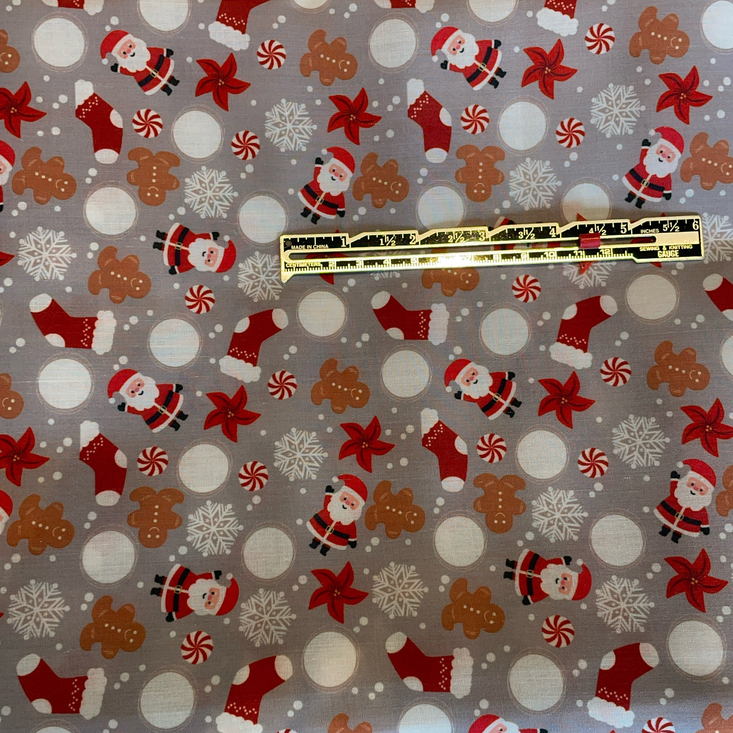 Christmas-themed fabric with Santa Claus, gingerbread men, and snowflakes on a gray background.