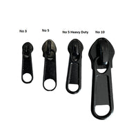 Four black zipper pullers of different sizes on a white background