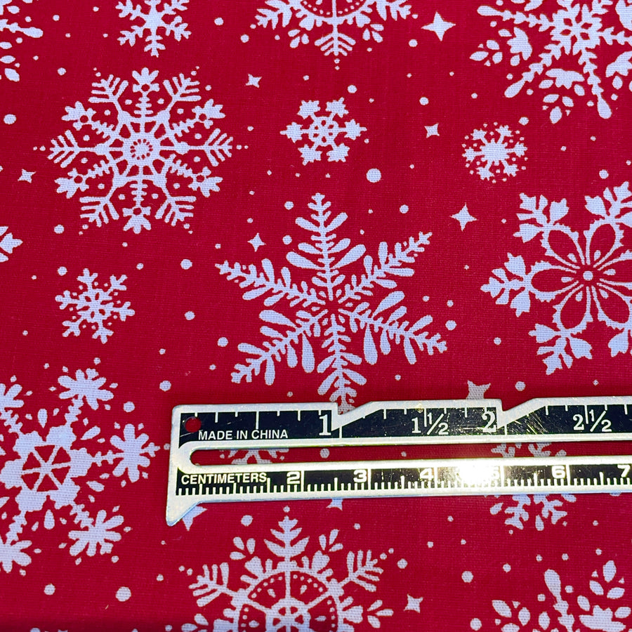 Red fabric with white snowflakes and a ruler for scale on a red background
