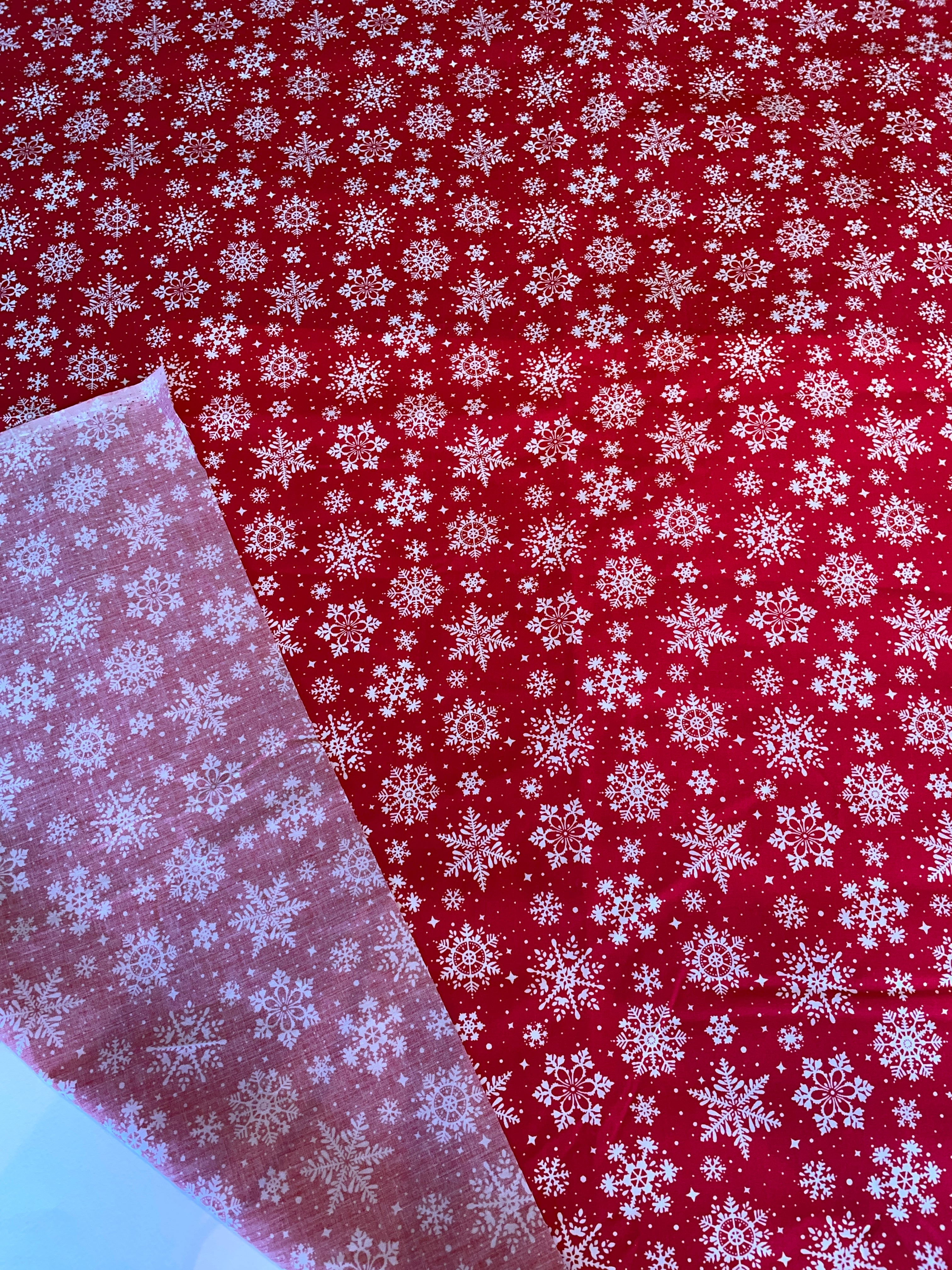 Red fabric with white snowflake pattern, showing a close-up of the texture.