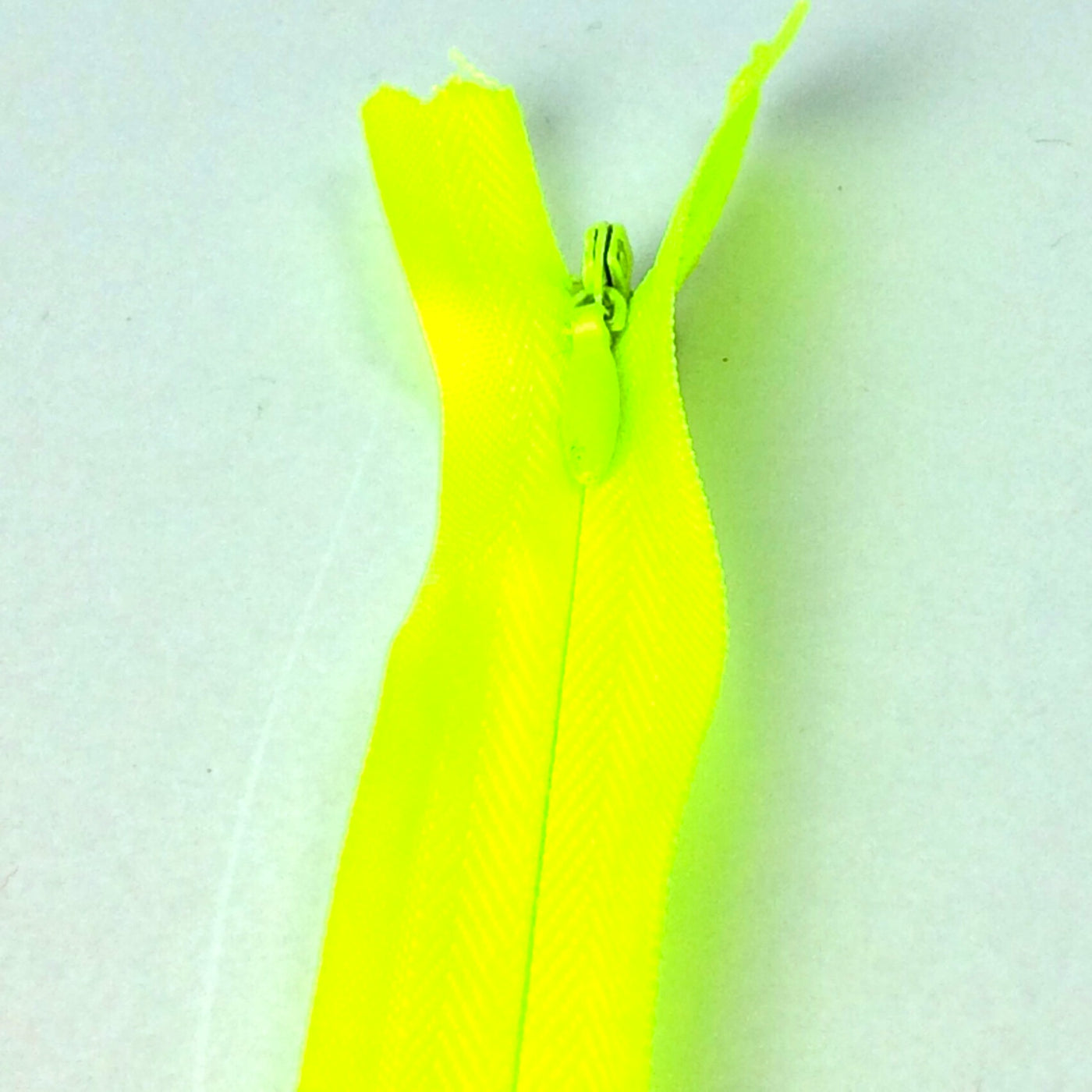 Photo of bright neon lime green yellow invisible or concealed zips available in many different colours and sizes. Great for achieving a professional finish in your products. Invisible zippers are perfect for dressmaking, cushions, crafts, etc., where you don't want your zipper showing. Installing them can be tricky without the right foot on your machine; a normal zipper foot is for installing standard zippers, while you will need an invisible zipper foot for a professional result