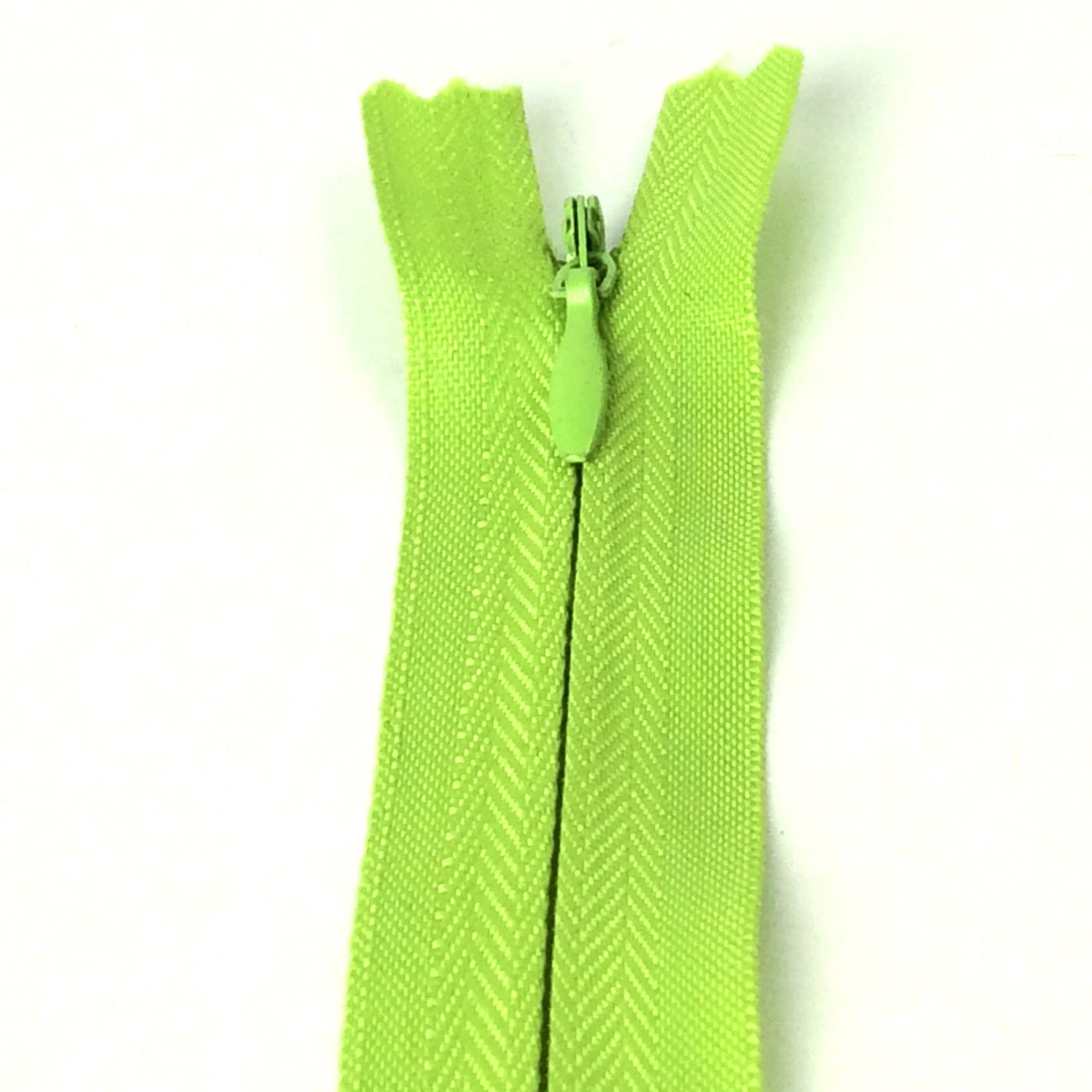Photo of light green invisible or concealed zips available in many different colours and sizes. Great for achieving a professional finish in your products. Invisible zippers are perfect for dressmaking, cushions, crafts, etc., where you don't want your zipper showing. Installing them can be tricky without the right foot on your machine; a normal zipper foot is for installing standard zippers, while you will need an invisible zipper foot for a professional result
