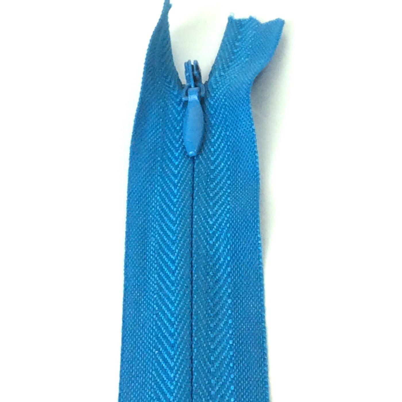 Photo of turquoise invisible or concealed zips available in many different colours and sizes. Great for achieving a professional finish in your products. Invisible zippers are perfect for dressmaking, cushions, crafts, etc., where you don't want your zipper showing. Installing them can be tricky without the right foot on your machine; a normal zipper foot is for installing standard zippers, while you will need an invisible zipper foot for a professional result