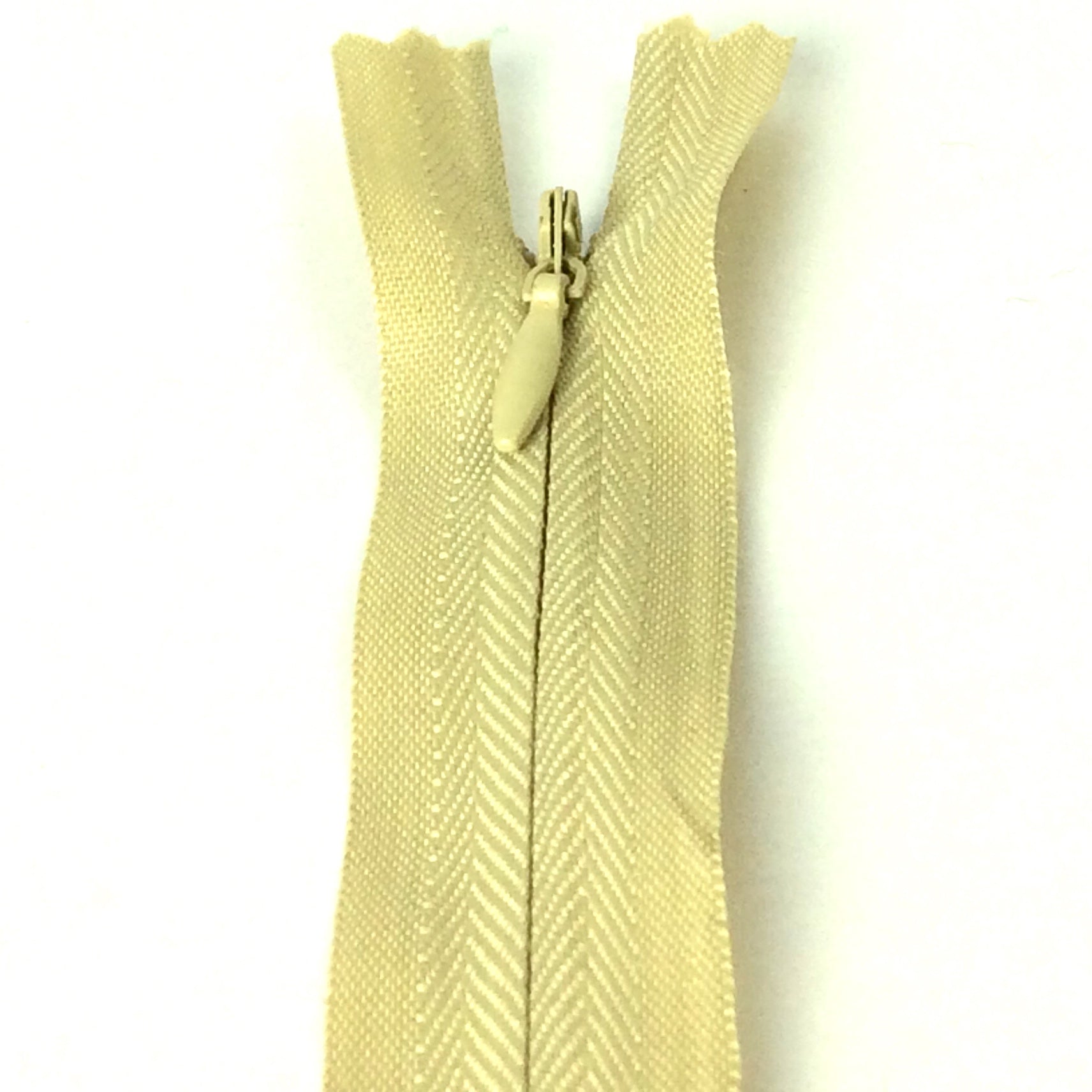 Photo of darker beige invisible or concealed zips available in many different colours and sizes. Great for achieving a professional finish in your products. Invisible zippers are perfect for dressmaking, cushions, crafts, etc., where you don't want your zipper showing. Installing them can be tricky without the right foot on your machine; a normal zipper foot is for installing standard zippers, while you will need an invisible zipper foot for a professional result