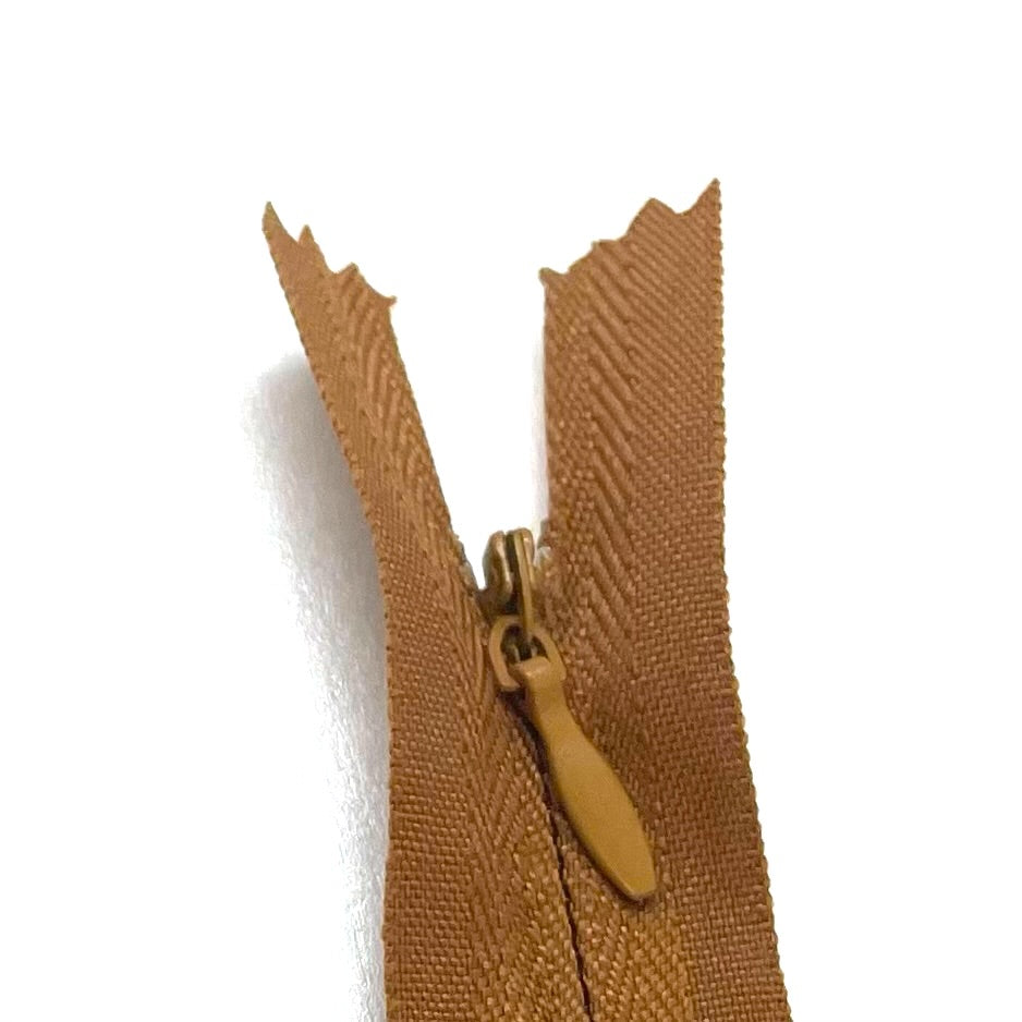 Photo of golden brown invisible or concealed zips available in many different colours and sizes. Great for achieving a professional finish in your products. Invisible zippers are perfect for dressmaking, cushions, crafts, etc., where you don't want your zipper showing. Installing them can be tricky without the right foot on your machine; a normal zipper foot is for installing standard zippers, while you will need an invisible zipper foot for a professional result