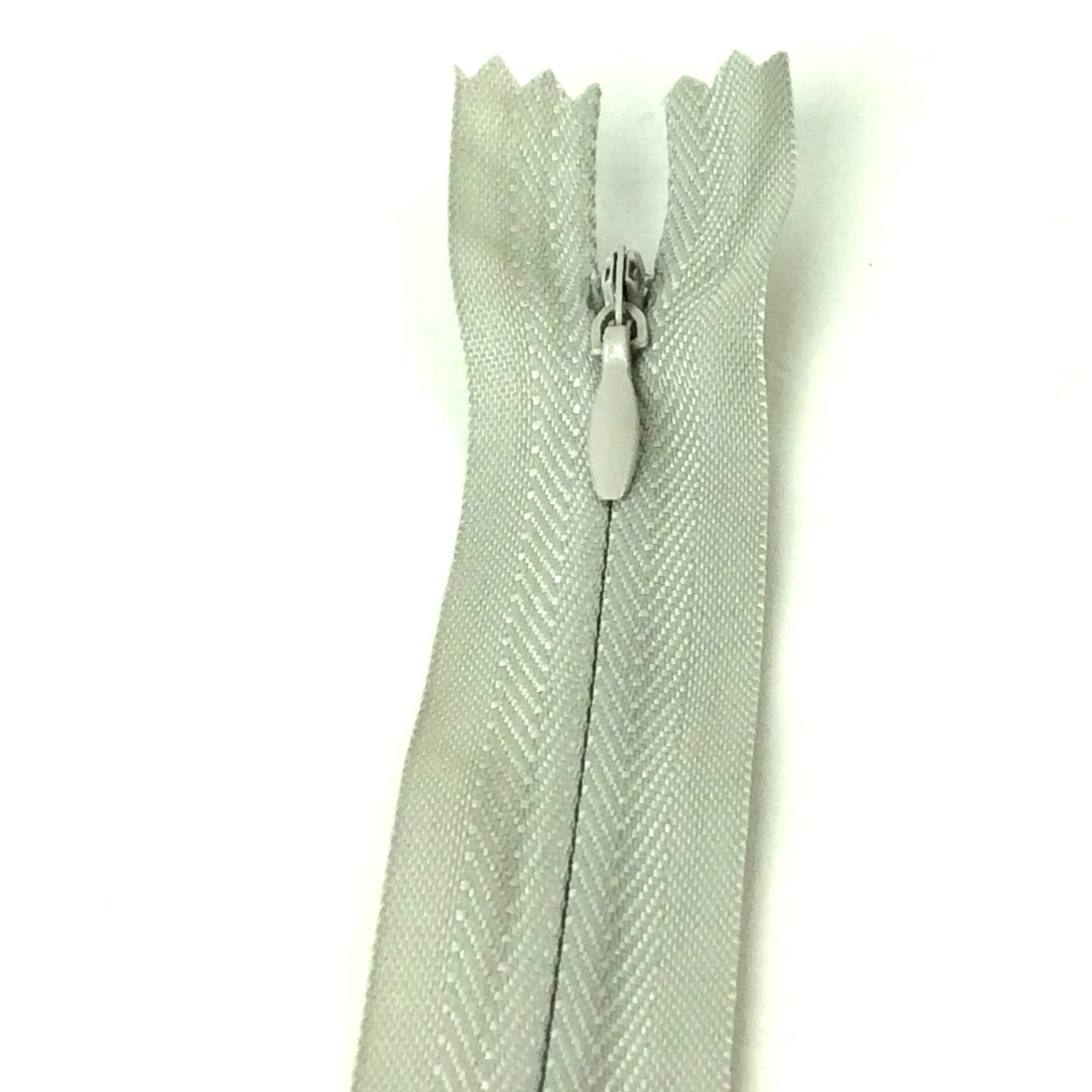 Photo of light grey invisible or concealed zips available in many different colours and sizes. Great for achieving a professional finish in your products. Invisible zippers are perfect for dressmaking, cushions, crafts, etc., where you don't want your zipper showing. Installing them can be tricky without the right foot on your machine; a normal zipper foot is for installing standard zippers, while you will need an invisible zipper foot for a professional result