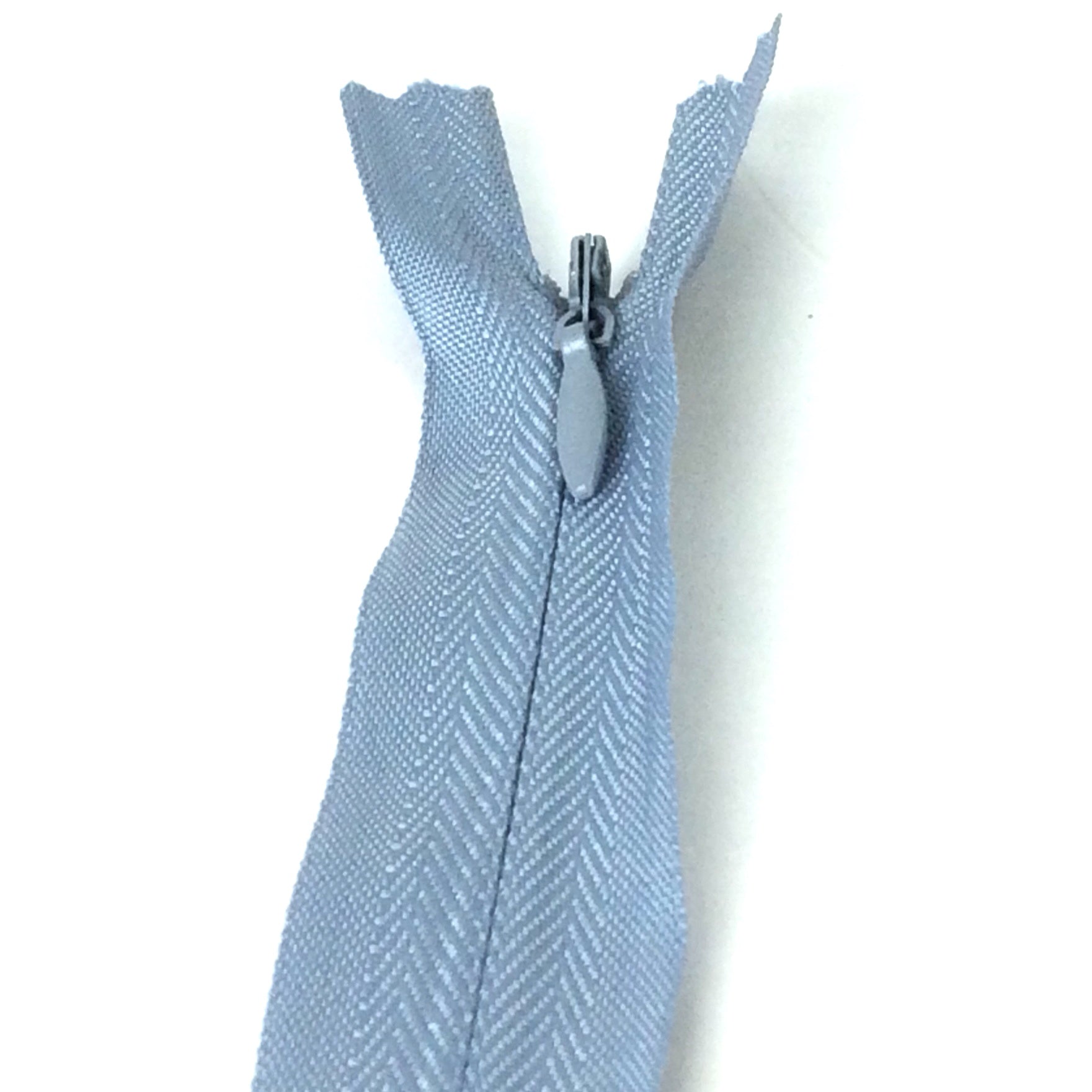 Photo of grey invisible or concealed zips available in many different colours and sizes. Great for achieving a professional finish in your products. Invisible zippers are perfect for dressmaking, cushions, crafts, etc., where you don't want your zipper showing. Installing them can be tricky without the right foot on your machine; a normal zipper foot is for installing standard zippers, while you will need an invisible zipper foot for a professional result
