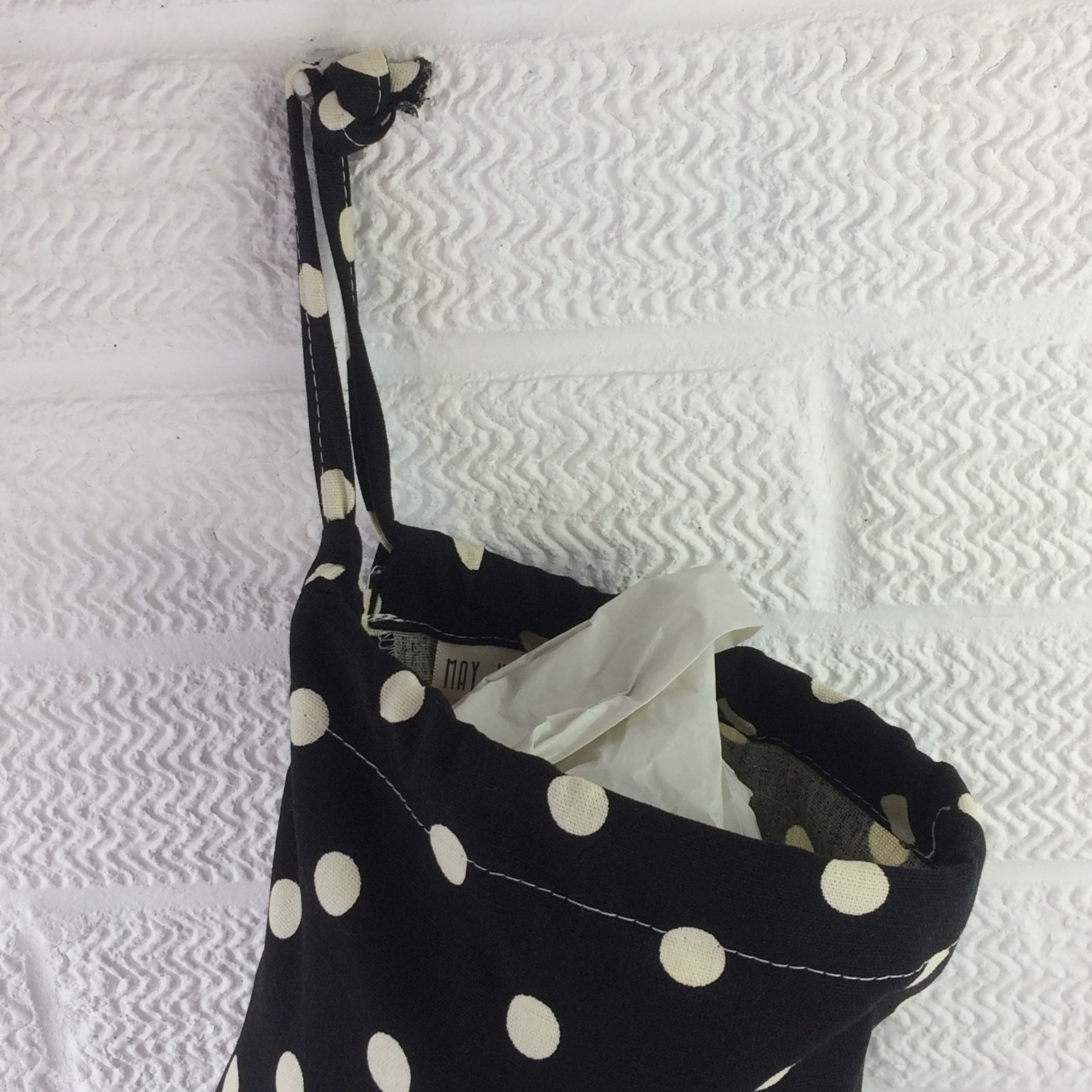 Plastic bag storage dispenser with large spots on a black background with drawstring top
