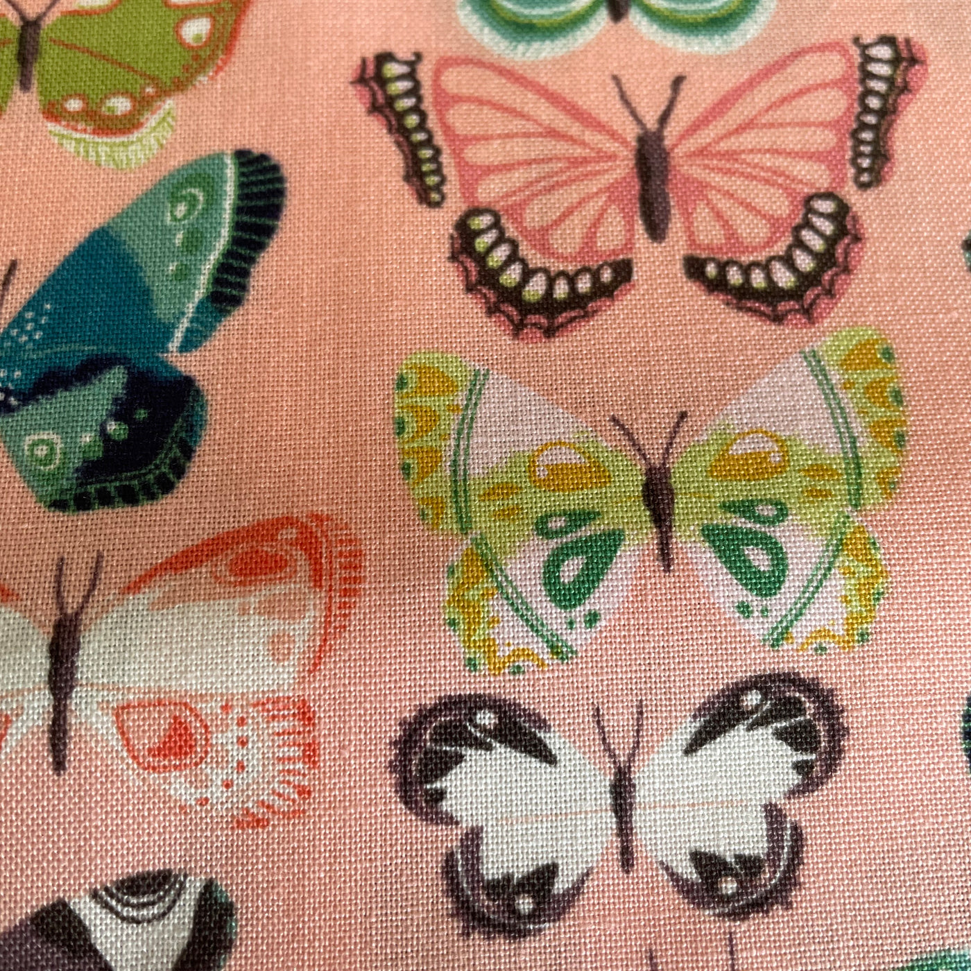 Riley Blakes middsummer meadow with butterflies on a salmon pink background
